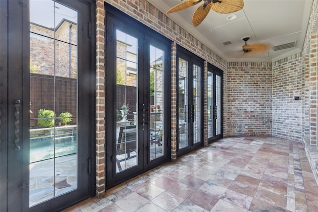 doorway to outside with french doors, ceiling fan, crown molding, and brick wall