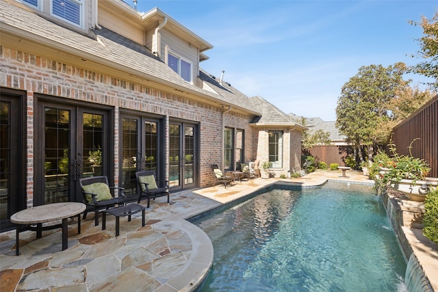 view of pool featuring french doors, pool water feature, and a patio