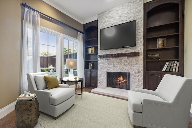 living room with ornamental molding, a fireplace, hardwood / wood-style floors, and built in features