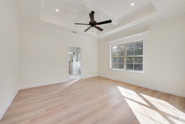 empty room with ornamental molding, light hardwood / wood-style flooring, ceiling fan, and a raised ceiling