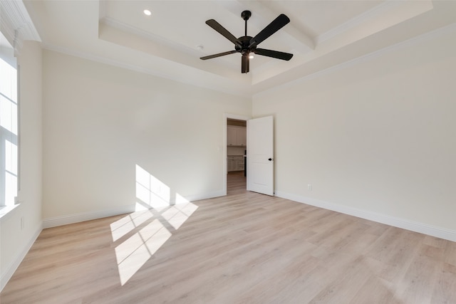 spare room with light hardwood / wood-style floors, ceiling fan, crown molding, a tray ceiling, and a high ceiling