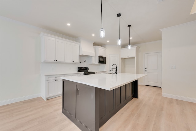 kitchen with black appliances, an island with sink, light hardwood / wood-style floors, and white cabinets