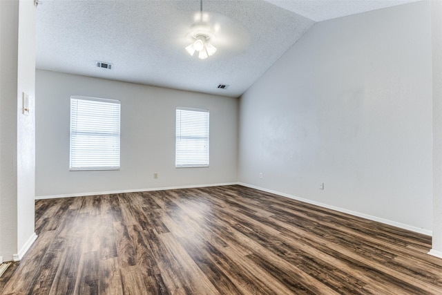 spare room with lofted ceiling, dark wood-type flooring, a textured ceiling, and ceiling fan