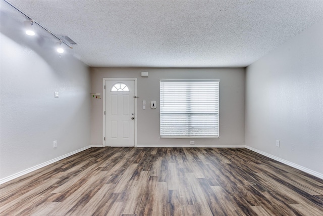 foyer entrance featuring dark hardwood / wood-style flooring, track lighting, and a textured ceiling