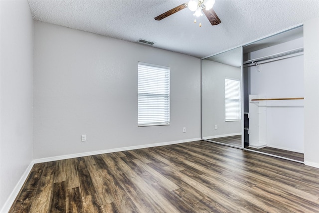 unfurnished bedroom with dark hardwood / wood-style flooring, a textured ceiling, ceiling fan, and a closet