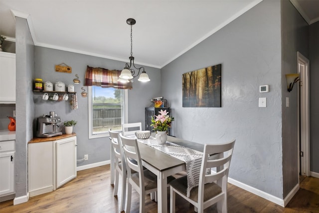 dining area featuring crown molding, an inviting chandelier, lofted ceiling, and light wood-type flooring