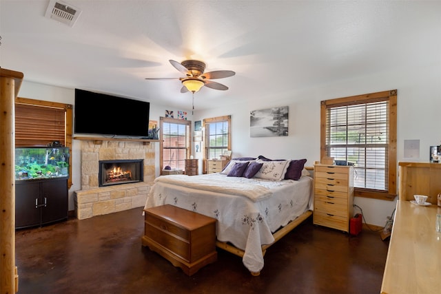 bedroom featuring a stone fireplace and ceiling fan