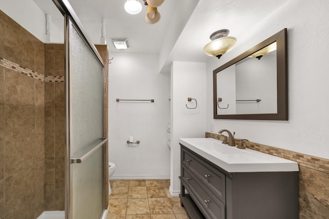 bathroom with vanity, toilet, and a shower with shower door