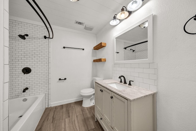 full bathroom featuring backsplash, vanity, tiled shower / bath combo, wood-type flooring, and toilet