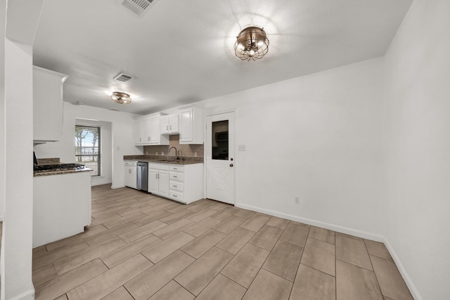 kitchen with sink, stainless steel dishwasher, dark stone countertops, decorative backsplash, and white cabinets