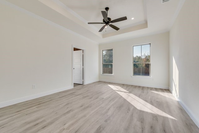 unfurnished room with crown molding, light hardwood / wood-style flooring, ceiling fan, and a raised ceiling