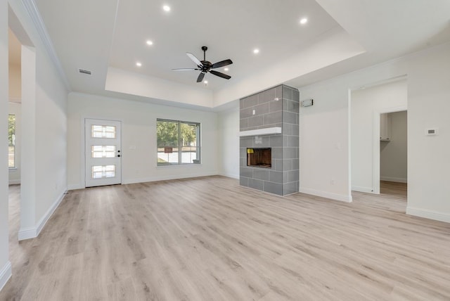 unfurnished living room with light hardwood / wood-style flooring, a raised ceiling, and a tile fireplace