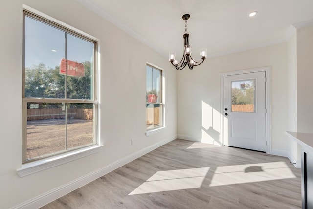 unfurnished dining area with a chandelier, a healthy amount of sunlight, light wood-type flooring, and crown molding