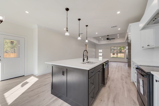 kitchen with white cabinetry, a center island with sink, sink, and light hardwood / wood-style flooring