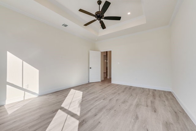 unfurnished room featuring light hardwood / wood-style floors, ceiling fan, crown molding, and a tray ceiling