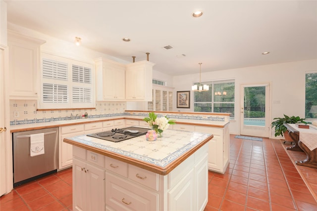 kitchen with stainless steel dishwasher, light tile patterned floors, black electric cooktop, decorative light fixtures, and a kitchen island