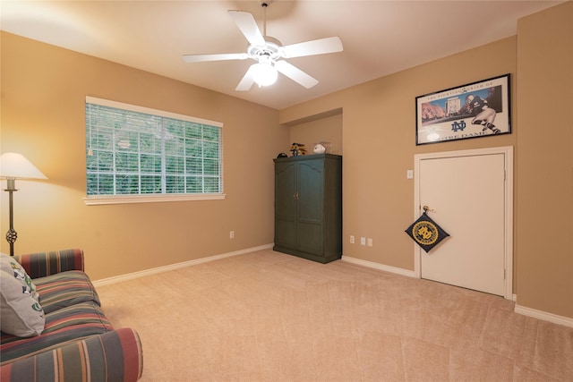 living area featuring ceiling fan and light colored carpet