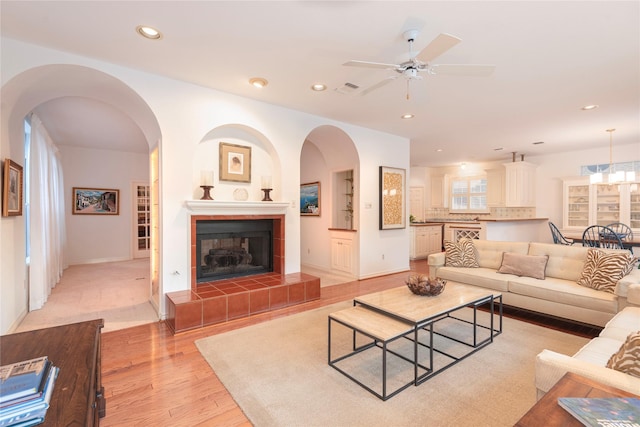 living room featuring ceiling fan, light hardwood / wood-style floors, and a fireplace