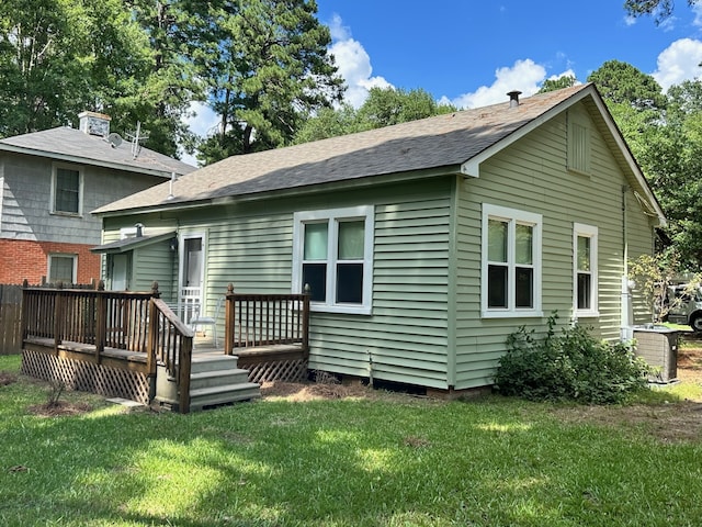 back of house featuring a lawn, a wooden deck, and central AC unit