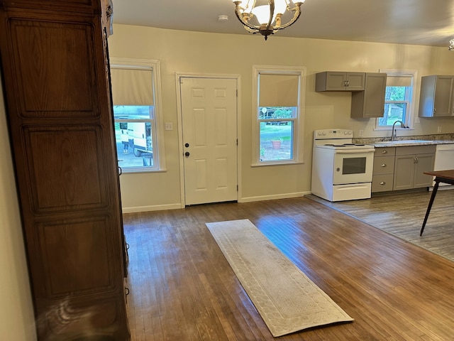 kitchen featuring dark hardwood / wood-style flooring, sink, white appliances, and a notable chandelier