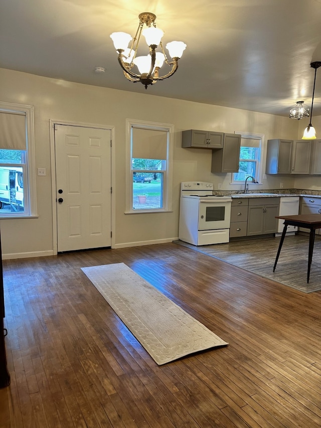 kitchen featuring dark hardwood / wood-style flooring, gray cabinetry, white appliances, decorative light fixtures, and an inviting chandelier