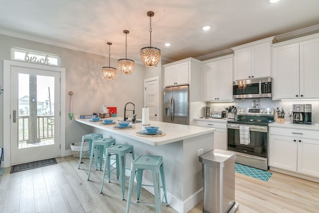 kitchen with hanging light fixtures, appliances with stainless steel finishes, white cabinetry, and backsplash