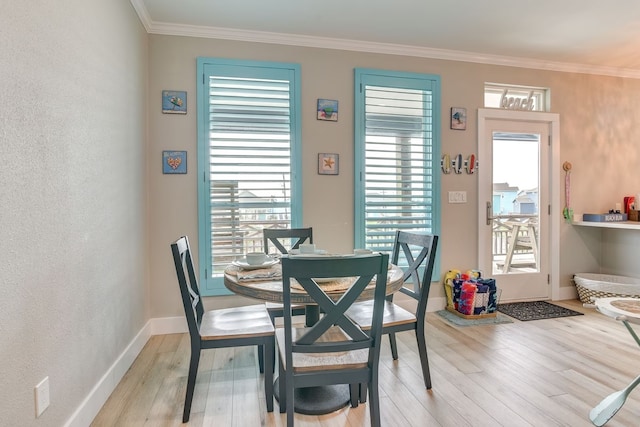 dining area featuring a healthy amount of sunlight, ornamental molding, and light hardwood / wood-style flooring