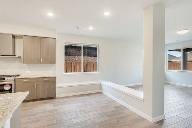 kitchen featuring light hardwood / wood-style floors, gas range, and wall chimney range hood