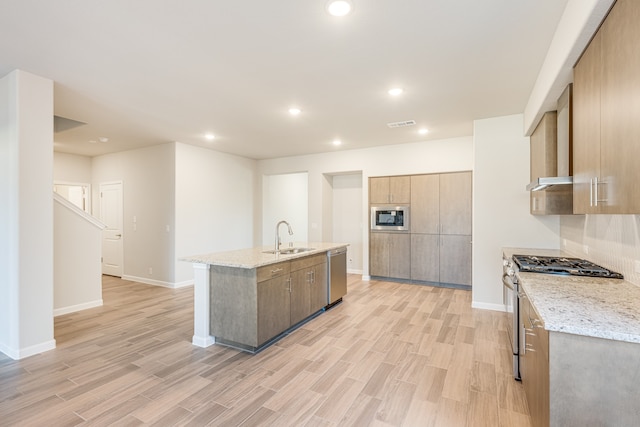 kitchen with stainless steel appliances, an island with sink, light wood-type flooring, and sink