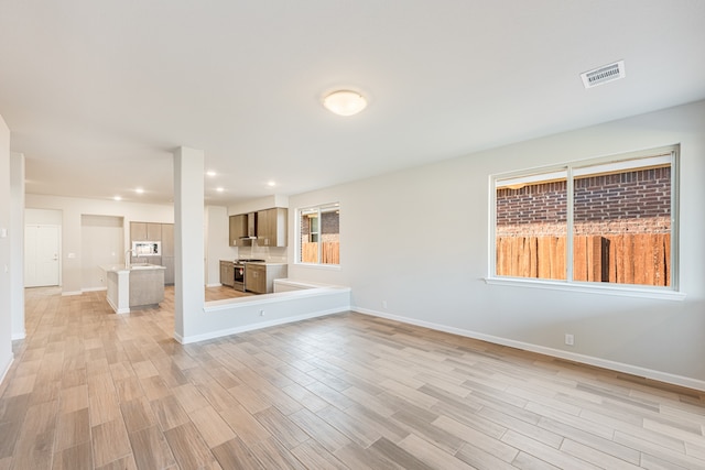 unfurnished living room with light wood-type flooring and a wealth of natural light