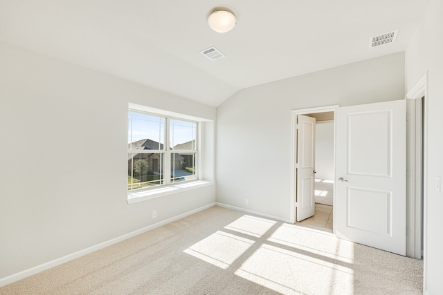 unfurnished bedroom featuring light carpet and vaulted ceiling