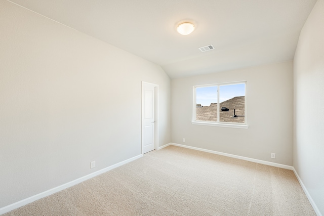 carpeted empty room with vaulted ceiling