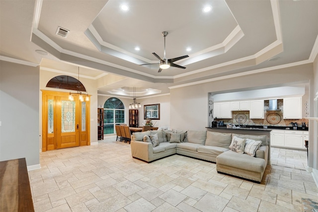 living room with ceiling fan with notable chandelier, a raised ceiling, and ornamental molding