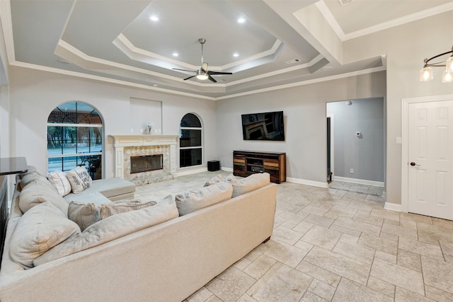 living room featuring a raised ceiling, ceiling fan, and crown molding