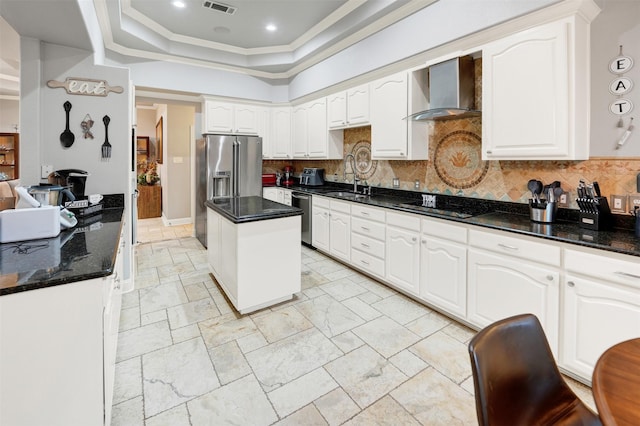 kitchen featuring white cabinets, wall chimney range hood, stainless steel appliances, and tasteful backsplash