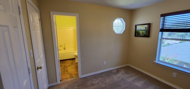 unfurnished bedroom with dark colored carpet, a closet, and a spacious closet