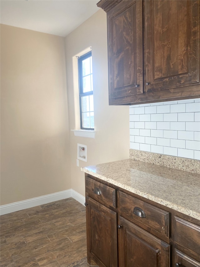 kitchen featuring dark brown cabinets, light stone counters, tasteful backsplash, and dark wood-type flooring