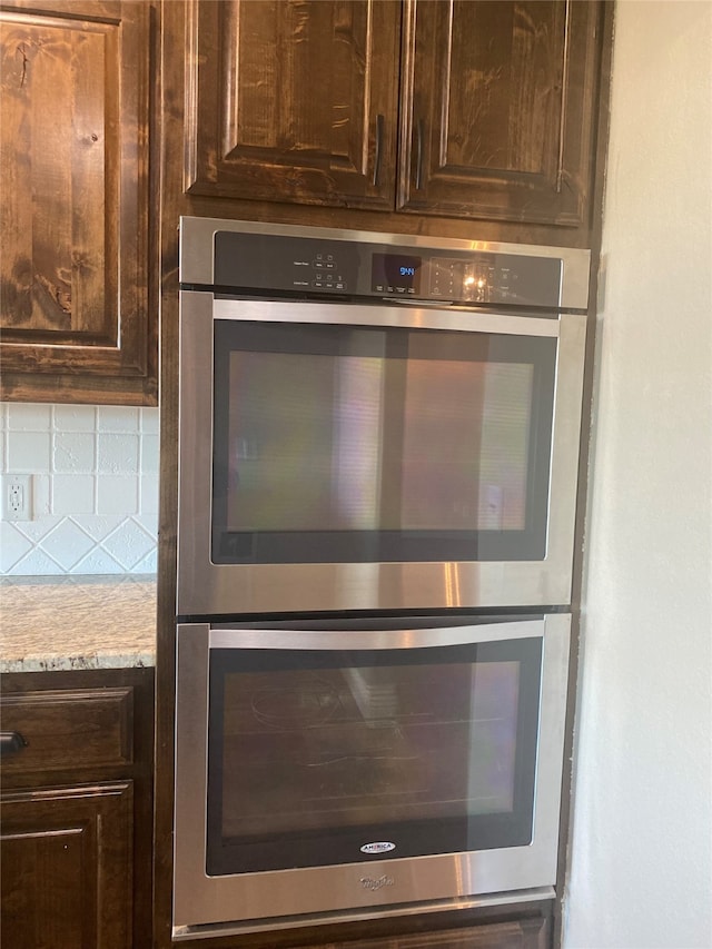 room details featuring dark brown cabinets, stainless steel double oven, tasteful backsplash, and light stone countertops