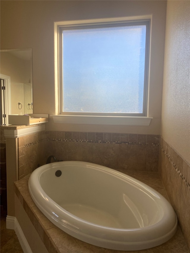 bathroom featuring plenty of natural light and tiled bath