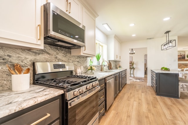 kitchen with pendant lighting, light stone countertops, white cabinetry, and appliances with stainless steel finishes