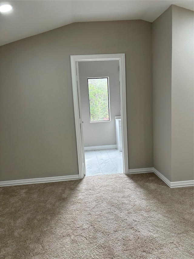 spare room with light tile flooring and lofted ceiling