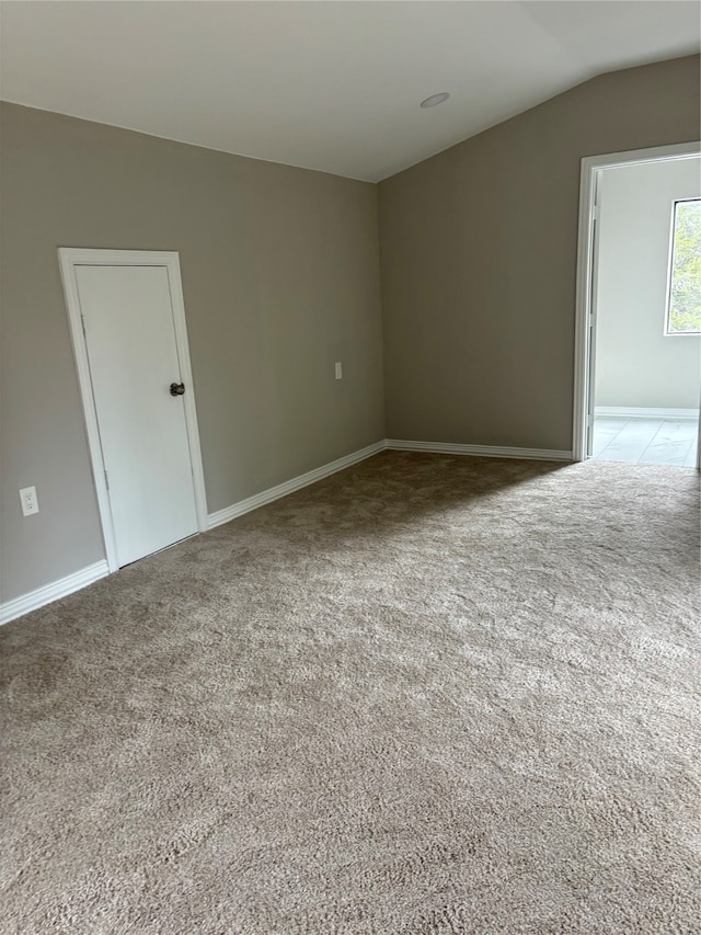 spare room featuring vaulted ceiling and light carpet