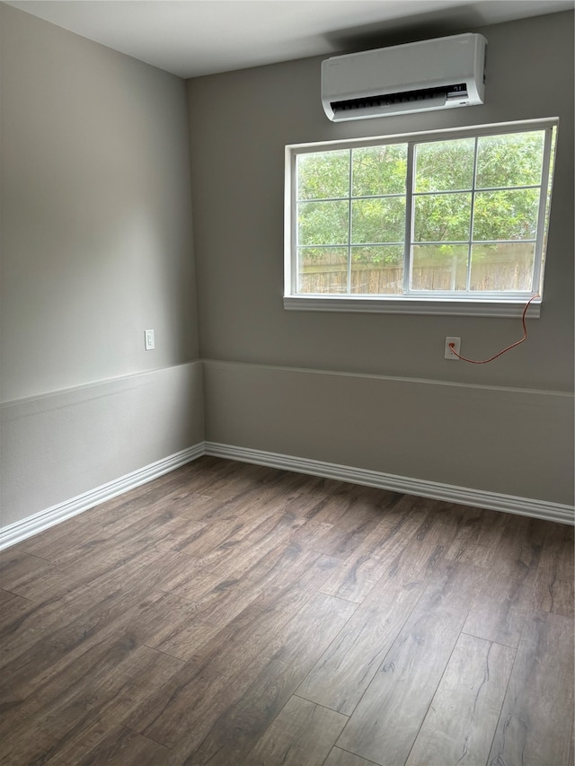 spare room with a wall unit AC and dark hardwood / wood-style floors