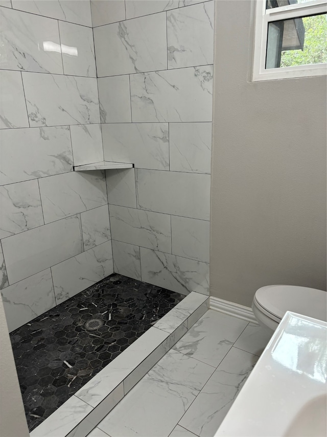 bathroom with tile floors, tiled shower, and toilet