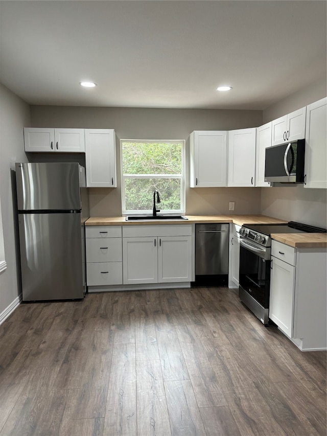 kitchen with white cabinetry, stainless steel appliances, hardwood / wood-style flooring, and sink