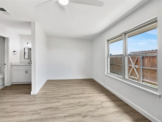 spare room with light wood-type flooring, ceiling fan, a healthy amount of sunlight, and sink