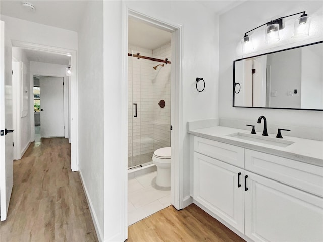 bathroom with vanity, toilet, hardwood / wood-style floors, and a shower with door