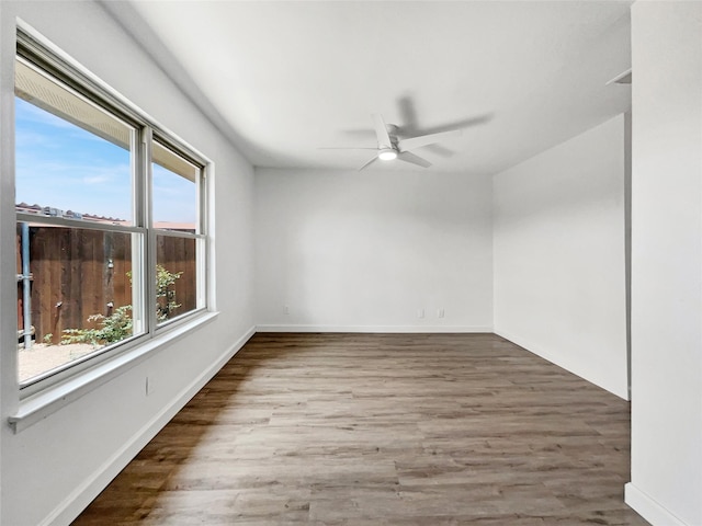 empty room with hardwood / wood-style flooring, a healthy amount of sunlight, and ceiling fan