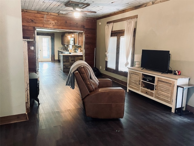 living room featuring a wealth of natural light, ceiling fan, wood walls, and dark hardwood / wood-style flooring