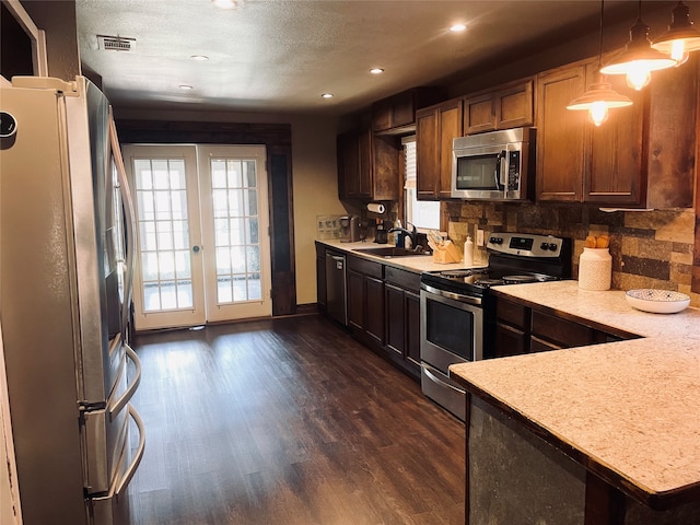 kitchen featuring dark hardwood / wood-style flooring, pendant lighting, backsplash, stainless steel appliances, and sink